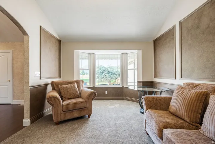 Bright corner bedroom suite with bay window seating area, dual built-in window benches with cushioned seating, neutral carpet flooring, and textured accent walls