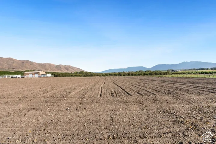 Expansive tilled agricultural land with distant mountain ranges and a clear sky backdrop