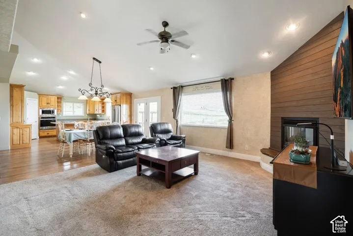 Vaulted ceilings with recessed lighting, wood-finish flooring, wood cabinetry with built-in appliances, a fireplace with a wood-paneled accent wall, and French doors