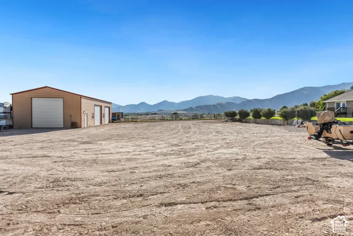 Large open lot with a tan and red-trimmed outbuilding featuring three garage doors