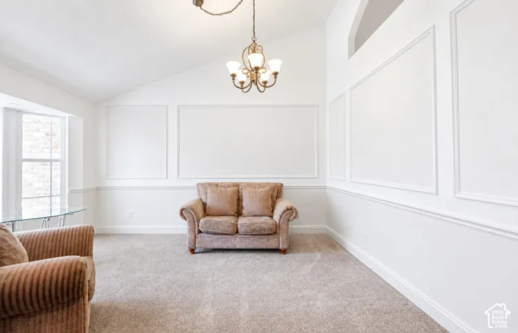 Digitally altered to show the room with white paint. Vaulted ceilings featuring decorative wall molding, wainscoting, and a multi-arm chandelier