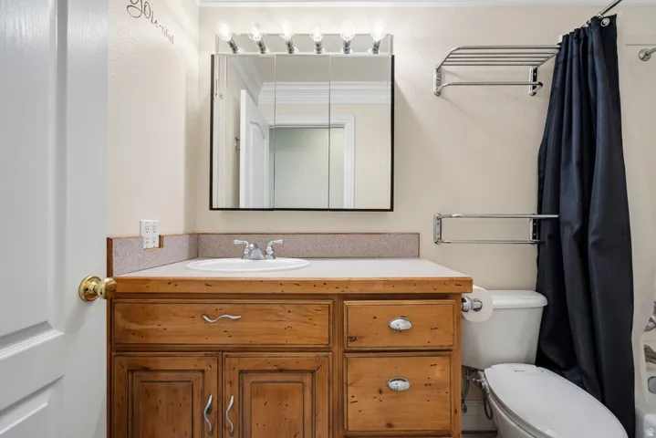 Vanity with wood-finish cabinetry, built-in sink, and laminate countertop