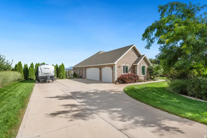 Brick exterior with a gabled roofline, three-car garage, and mature landscaping