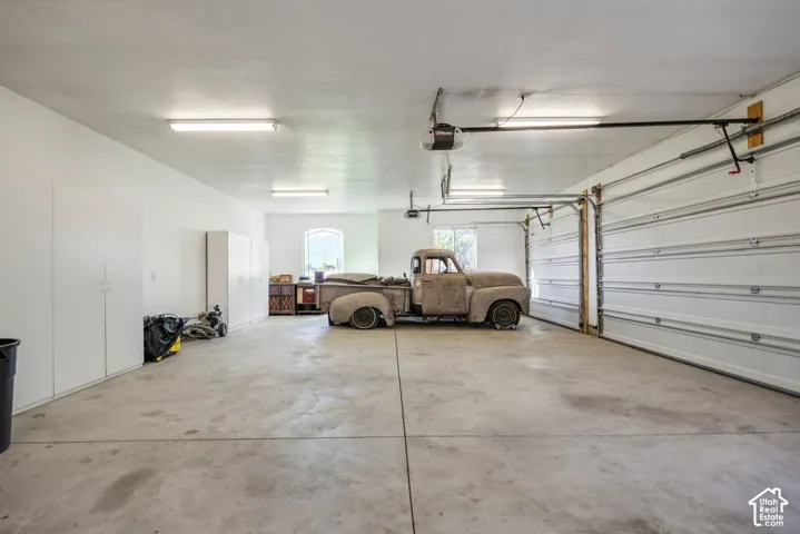 Spacious garage with concrete flooring, overhead lighting, and multiple storage cabinets  Antique truck is not for sale.