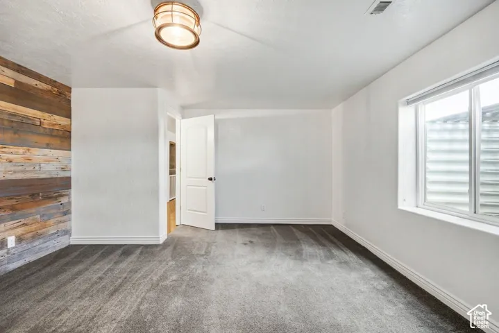 Textured wood accent wall, neutral carpeting, white interior paint, white trim, and a contemporary ceiling light fixture