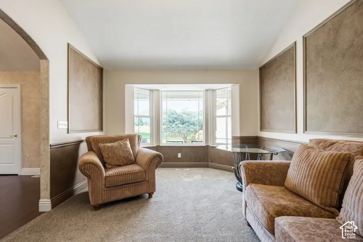 Bright corner bedroom suite with bay window seating area, dual built-in window benches with cushioned seating, neutral carpet flooring, and textured accent walls