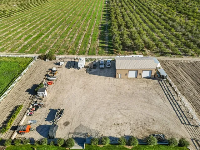 Expansive property featuring a large open lot, a  three-bay garage structure, and perimeter fencing