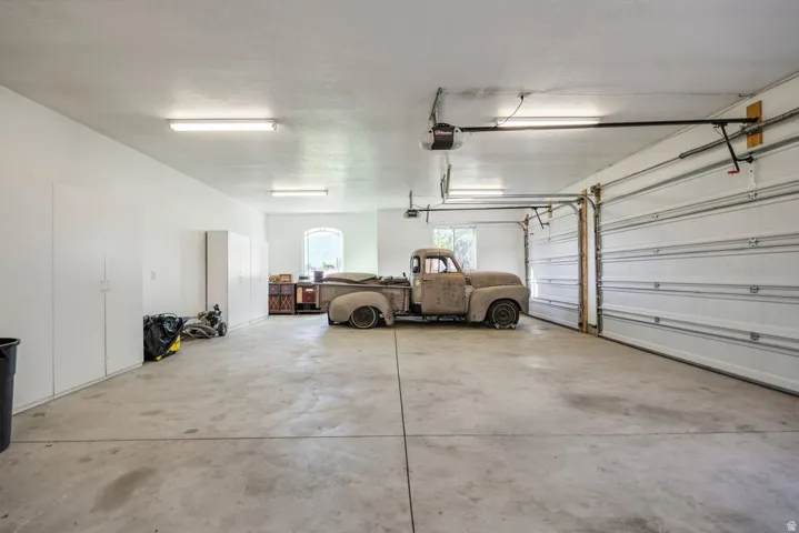 Spacious garage with concrete flooring, overhead lighting, and multiple storage cabinets  Antique truck is not for sale.