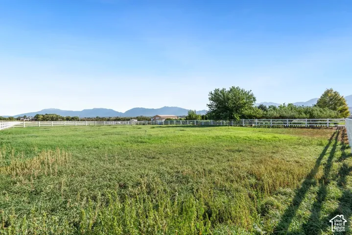 Expansive green space with white fencing and distant mountain scenery