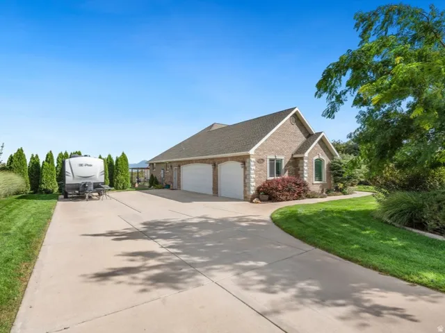 Brick exterior with a gabled roofline, three -car garage, and mature landscaping