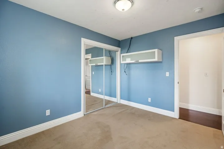Mirrored closet doors, flush-mount ceiling light, wall-mounted cabinet, and wood-finish flooring visible through the doorway.
