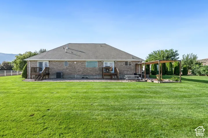 Expansive lawn area with a pergola, two wooden decks, and a brick exterior with a shingle roof