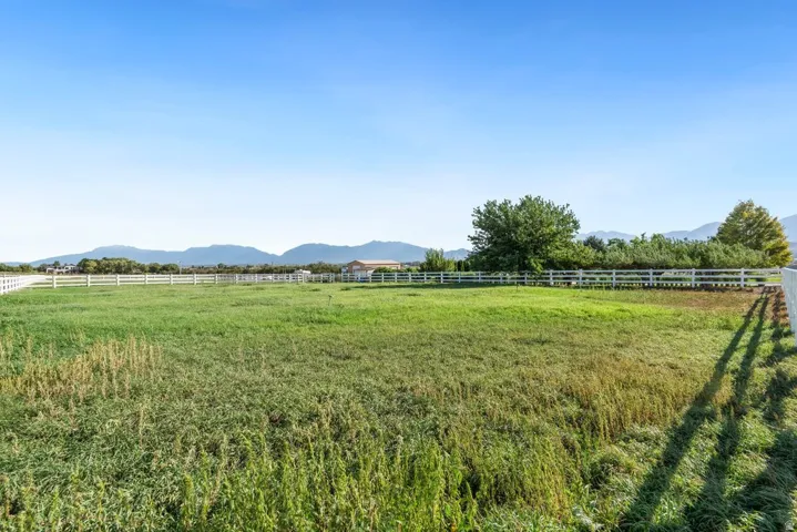 Expansive green space with white fencing and distant mountain scenery