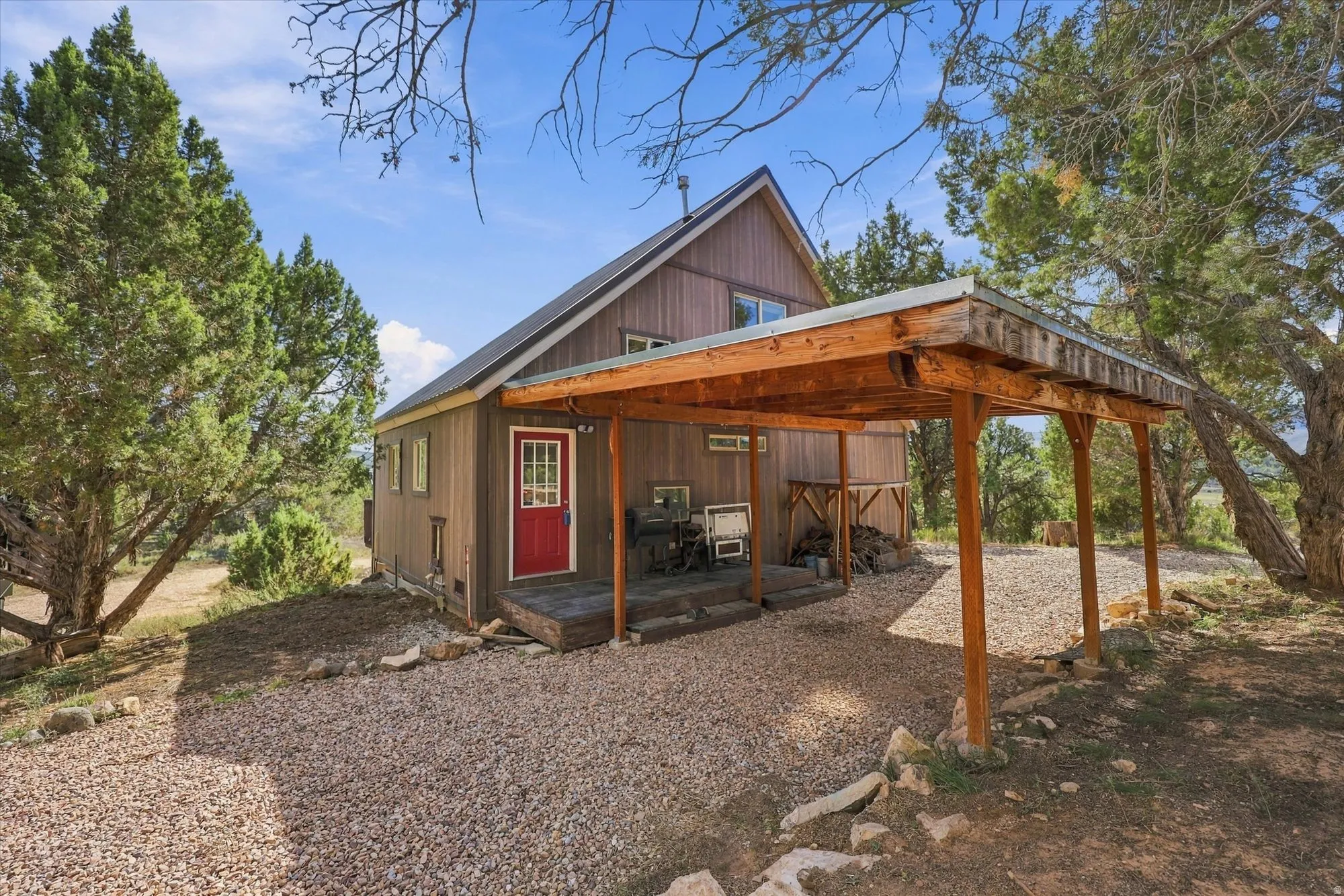 Wood-sided exterior with a sloped metal roof, covered wood deck, and an attached wood carport