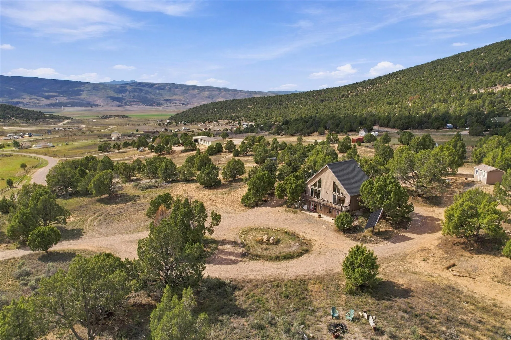 Mountain-backed property featuring a gable roof, exterior deck, and mature evergreen trees