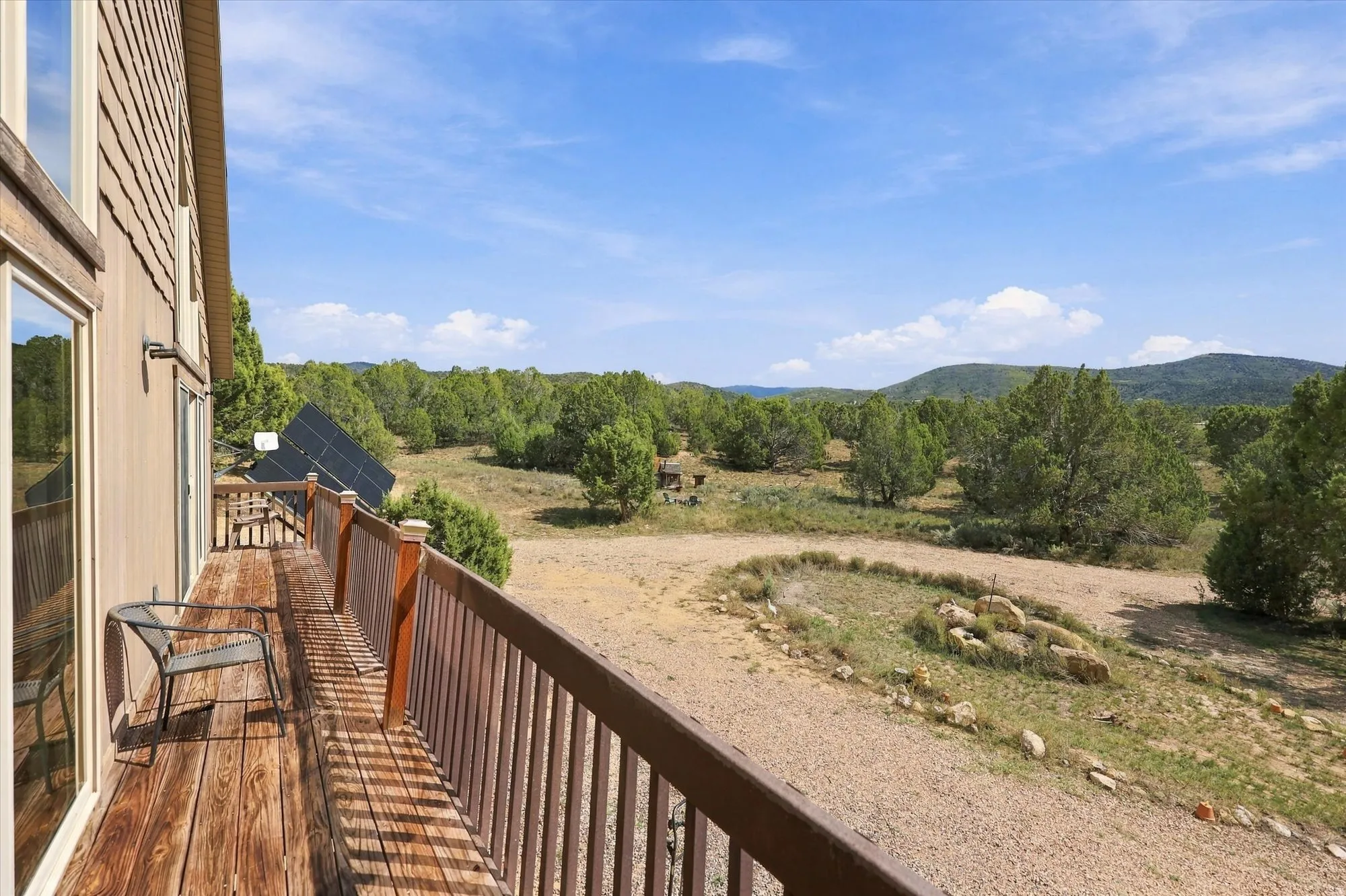 Spacious outdoor deck with wood-finish flooring and wood railing, offering expansive natural scenery