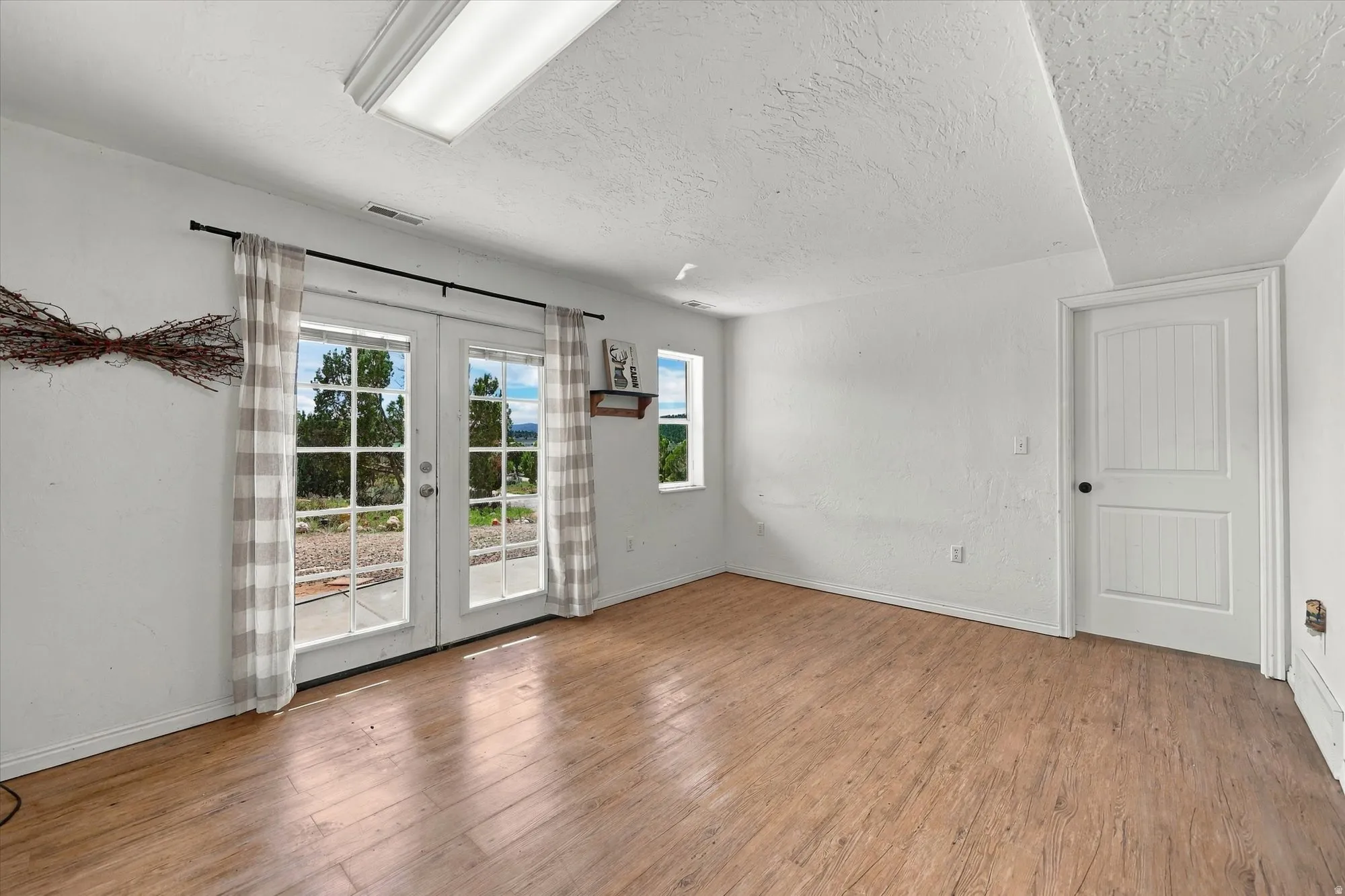 Recessed ceiling light, wood-finish flooring, white paneled door, French doors, multiple windows