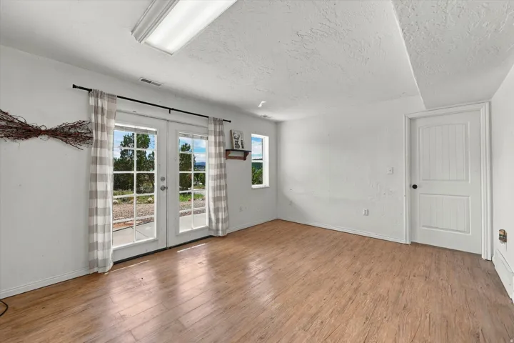 Recessed ceiling light, wood-finish flooring, white paneled door, French doors, multiple windows