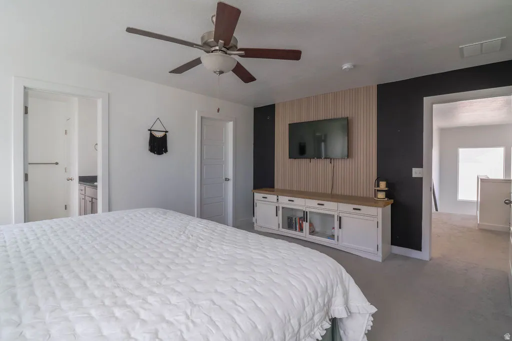 Ceiling fan with wood-finish blades, recessed lighting, and wall-mounted media console with storage