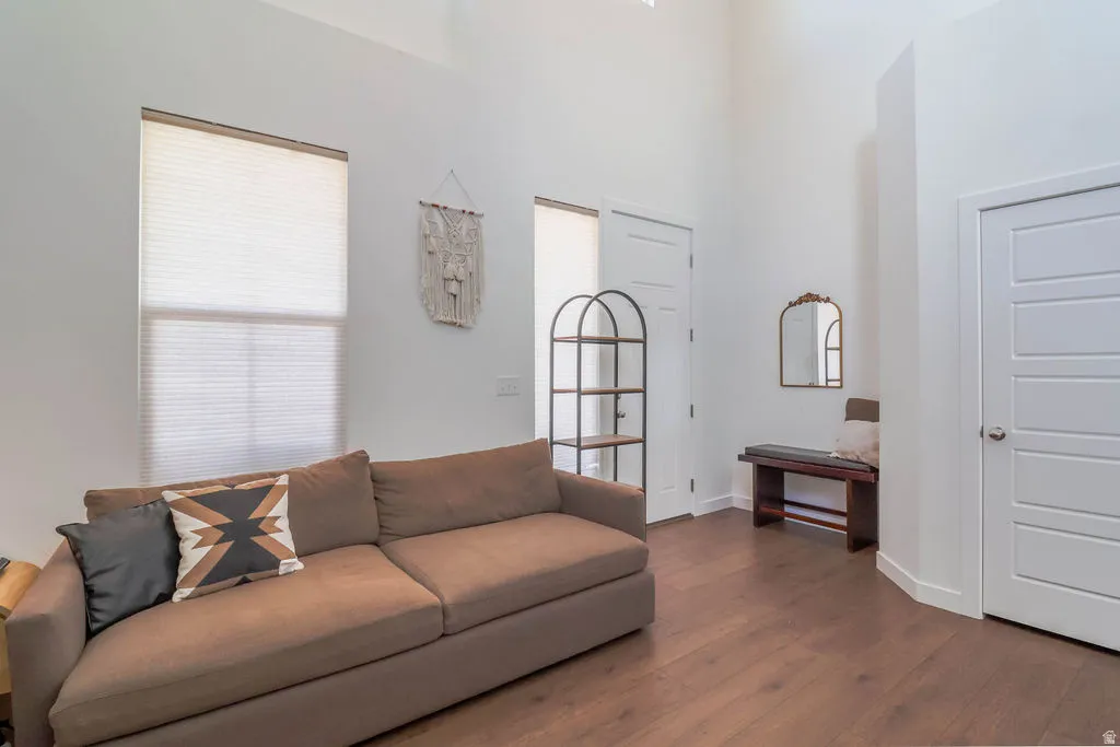 Tall ceilings, wood-finish flooring, white paneled doors, and natural light from the window