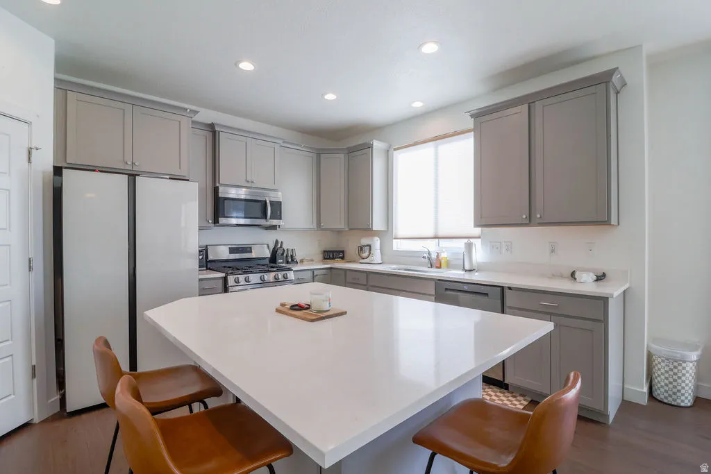 Modern kitchen featuring a large center island, recessed lighting, stainless steel appliances, and gray shaker-style cabinetry with crown molding