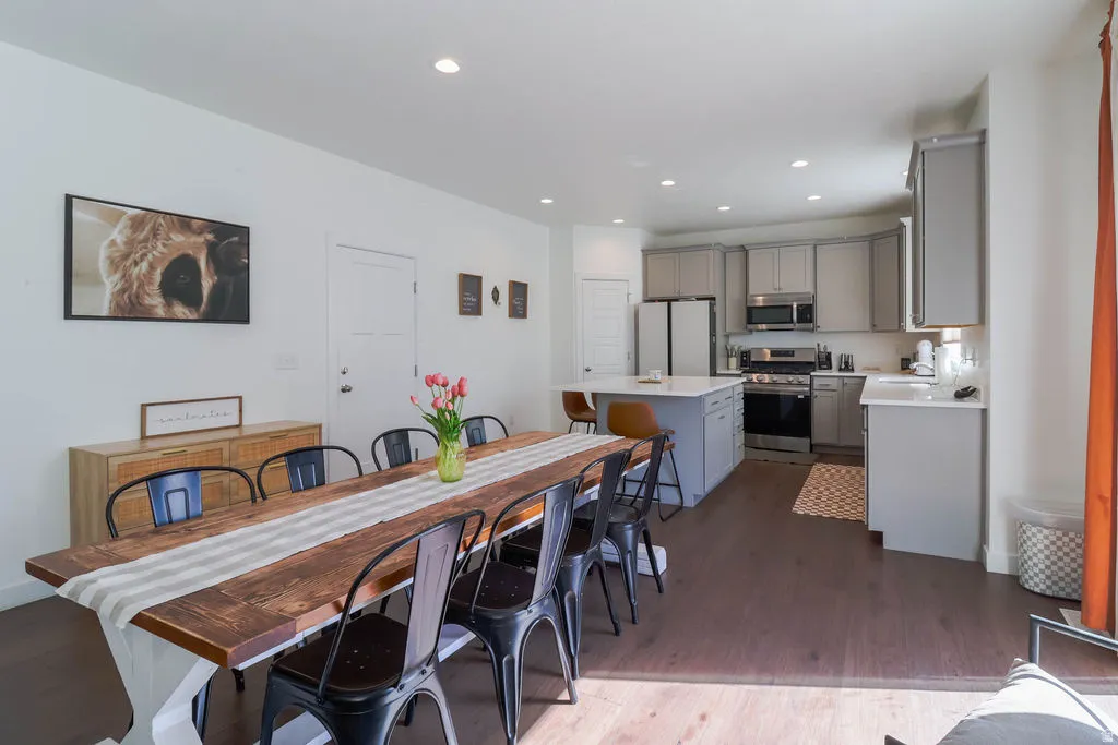 Open-concept living space with dark wood-finish flooring, recessed lighting, and a white interior door