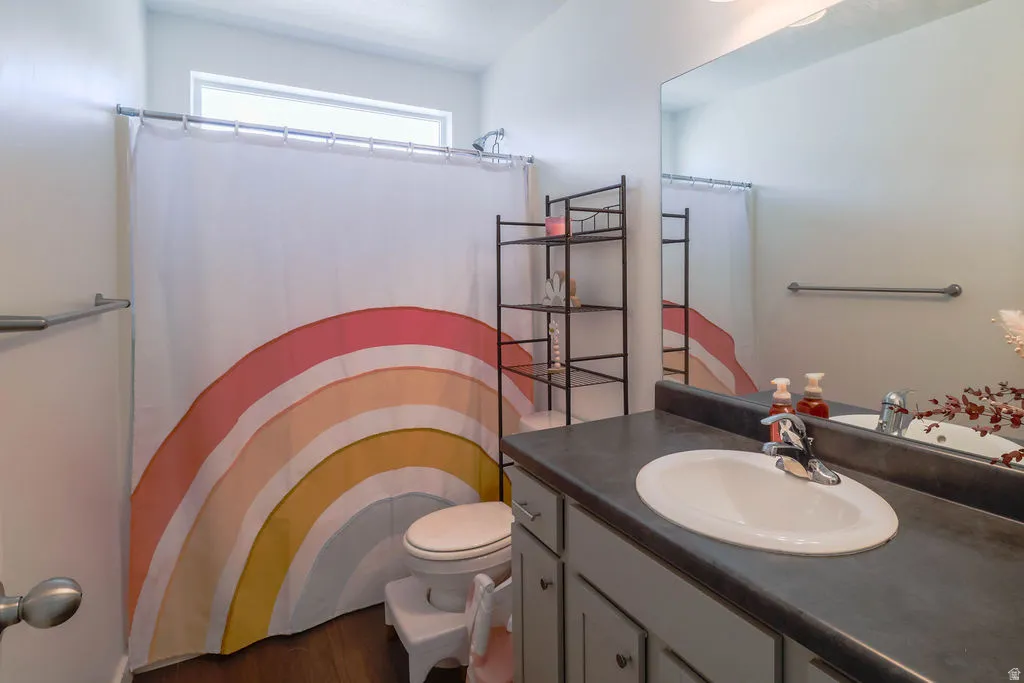 White oval sink with chrome faucet, dark countertop, and light gray cabinetry