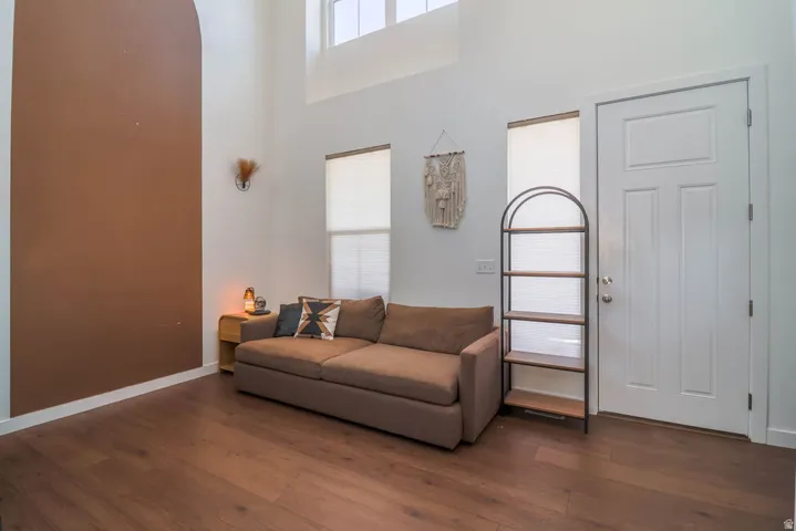 High ceilings with a prominent accent wall, wood-finish flooring, and multiple windows providing natural light