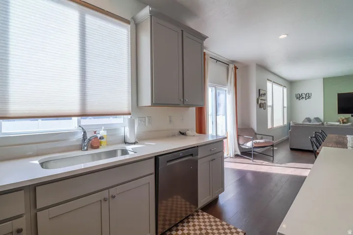 Kitchen featuring light gray cabinetry, stainless steel sink with a gooseneck faucet, light-toned countertop, and a stainless steel dishwasher