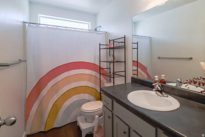 White oval sink with chrome faucet, dark countertop, and light gray cabinetry
