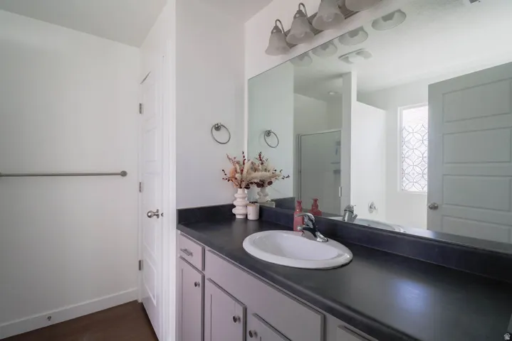 Vanity with an integrated white sink, dark countertop, and light-colored cabinetry