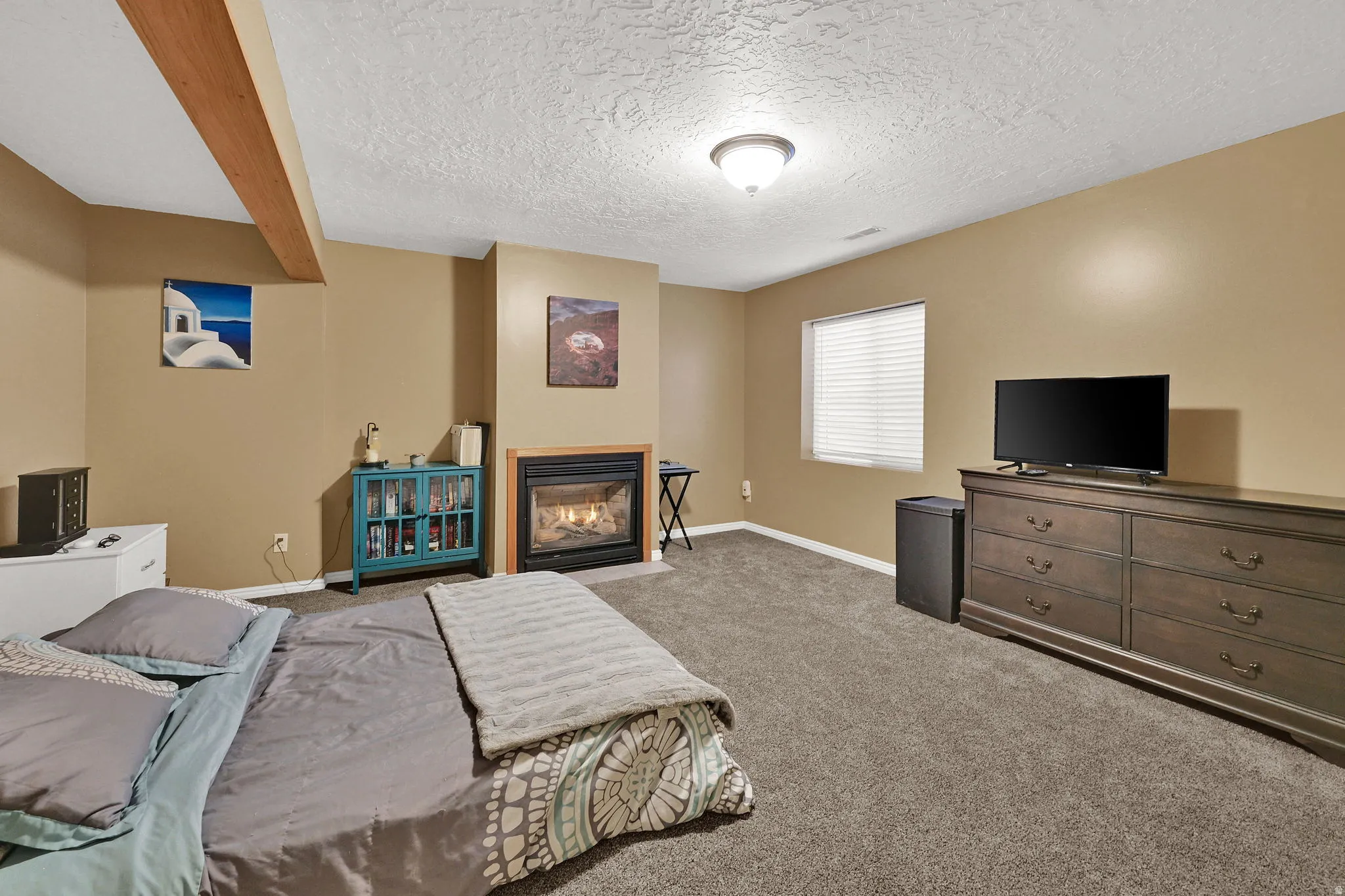 Built-in fireplace with a hearth, wood-finish ceiling beam, window with blinds, and recessed lighting