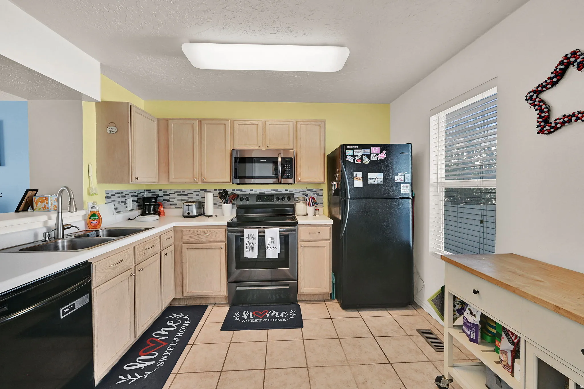 Kitchen featuring wood-finish cabinetry, tile flooring, and a window with blinds