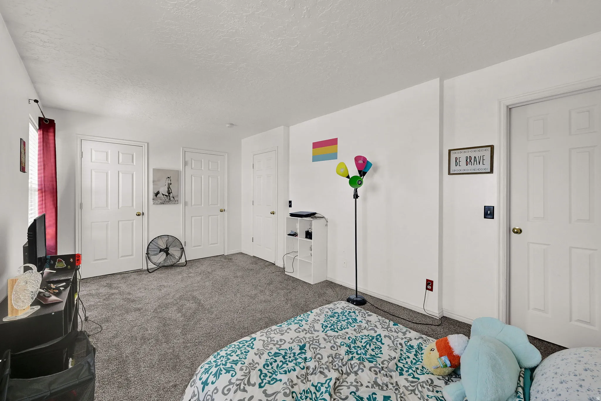 Neutral-toned carpeting, white interior doors with brass-finish hardware, and a window with vertical blinds
