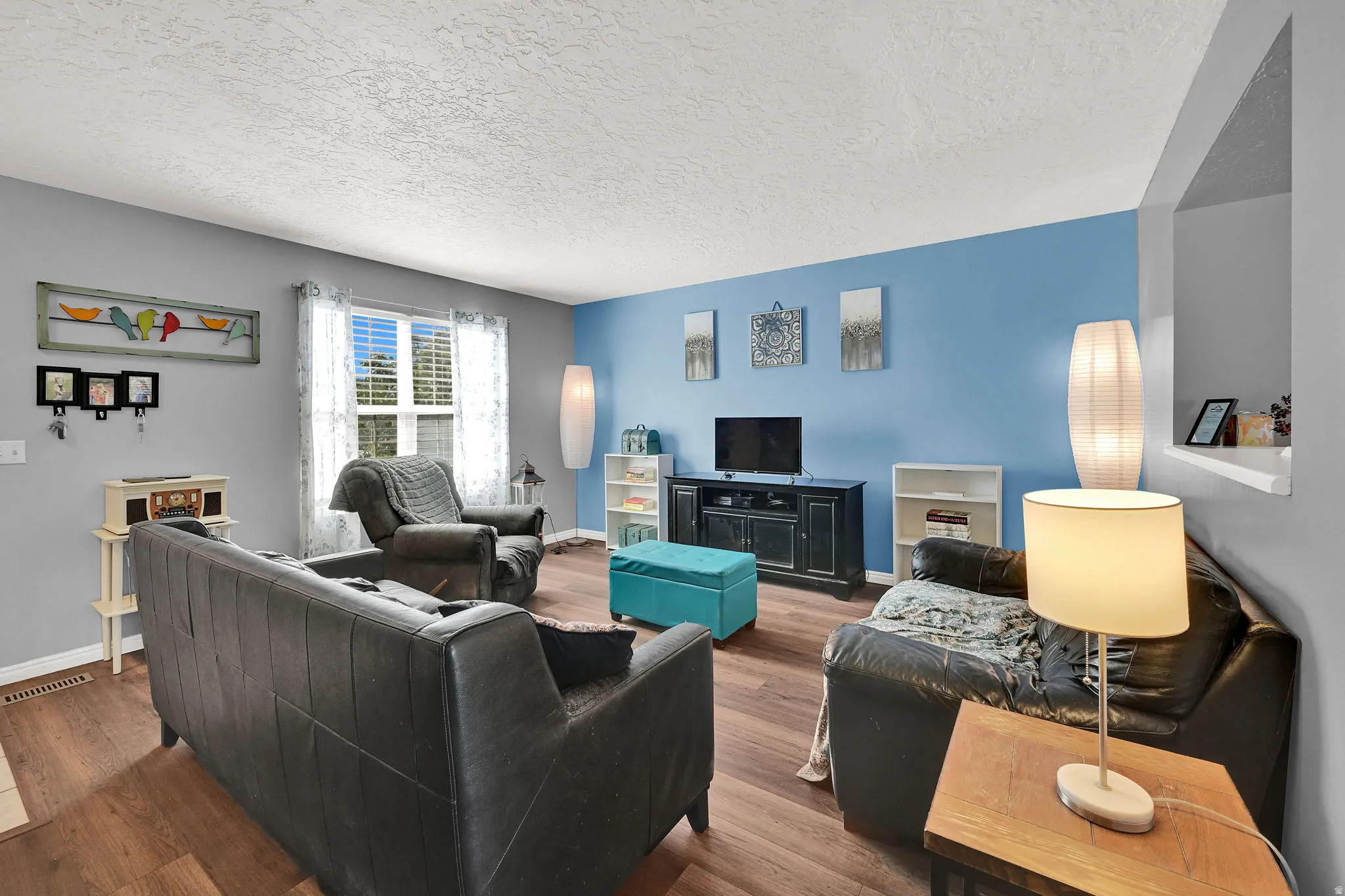 Wood-finish flooring throughout, a large window with horizontal blinds, and a built-in display niche