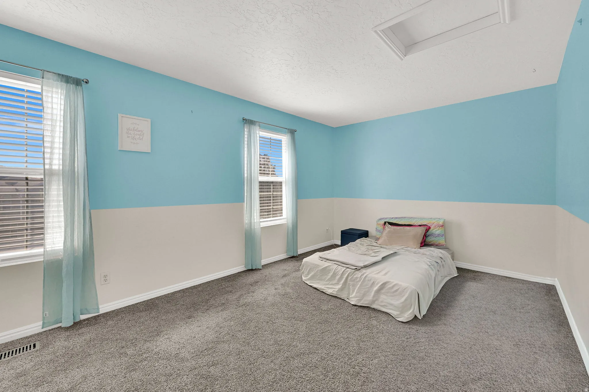 Carpeted room with two windows, two-tone wall paint, and a ceiling access panel