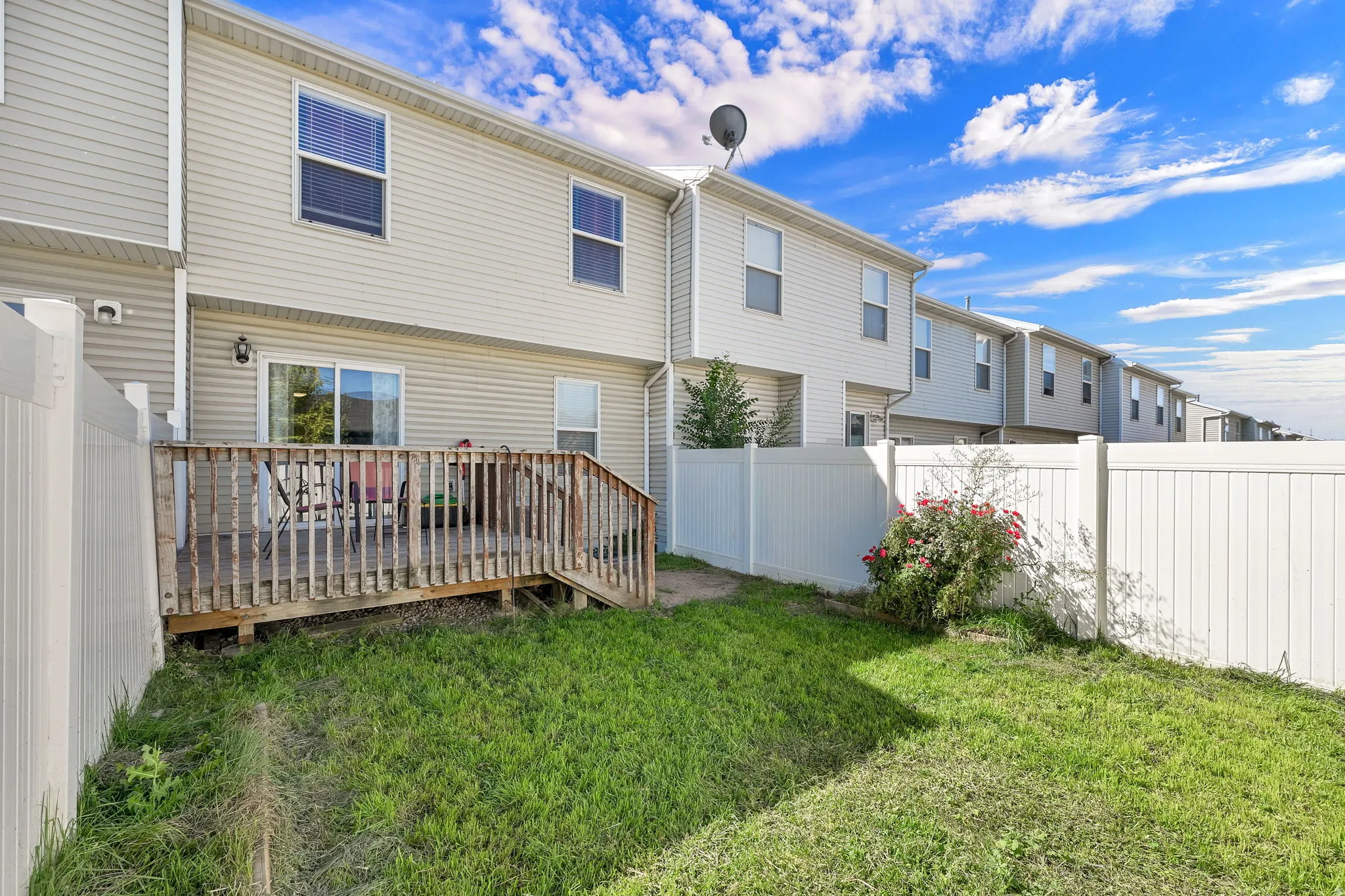 Private backyard with a wood deck, sliding glass door, and vinyl fencing