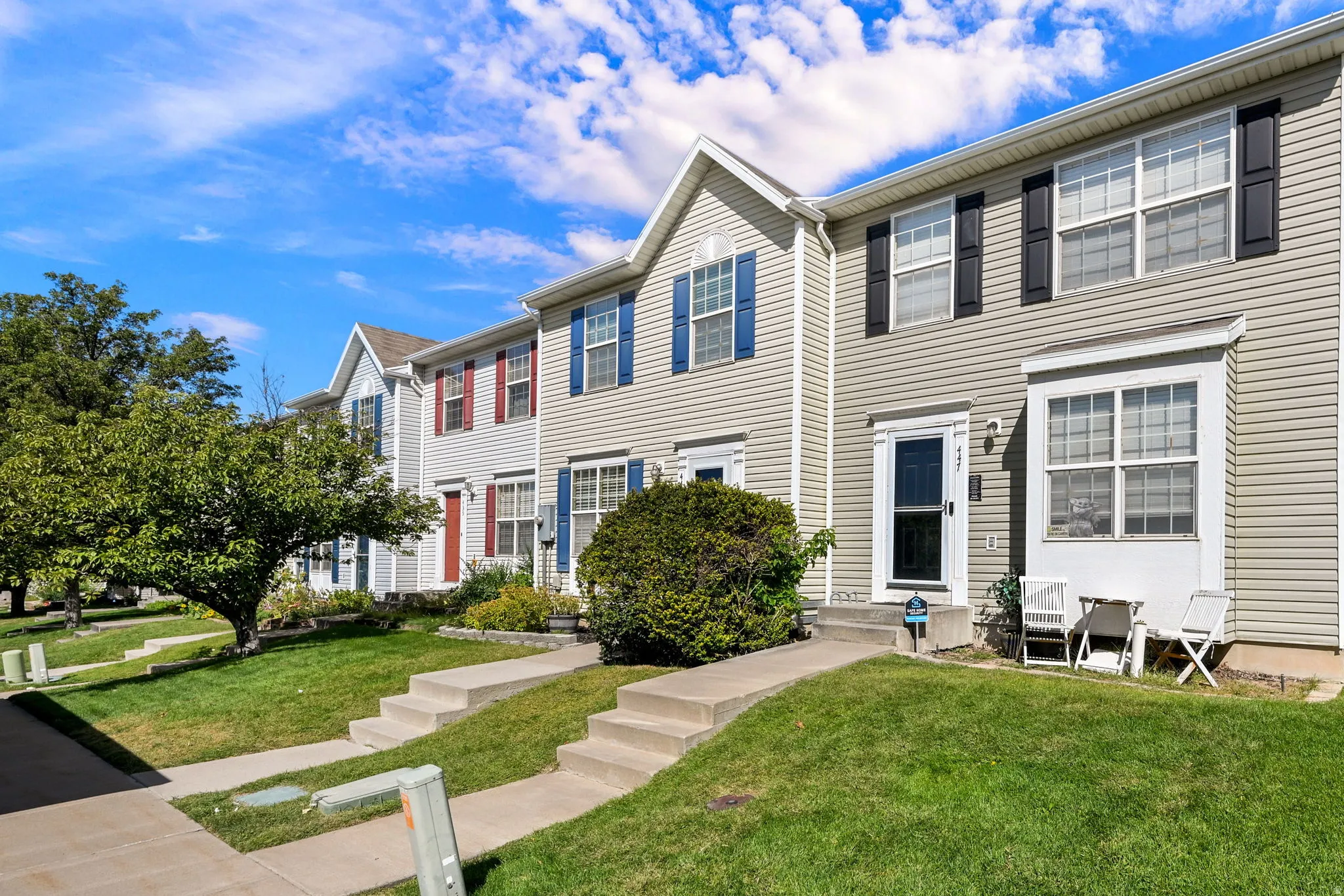 Vinyl siding exterior featuring contrasting window shutters, a prominent bay window, and a concrete walkway