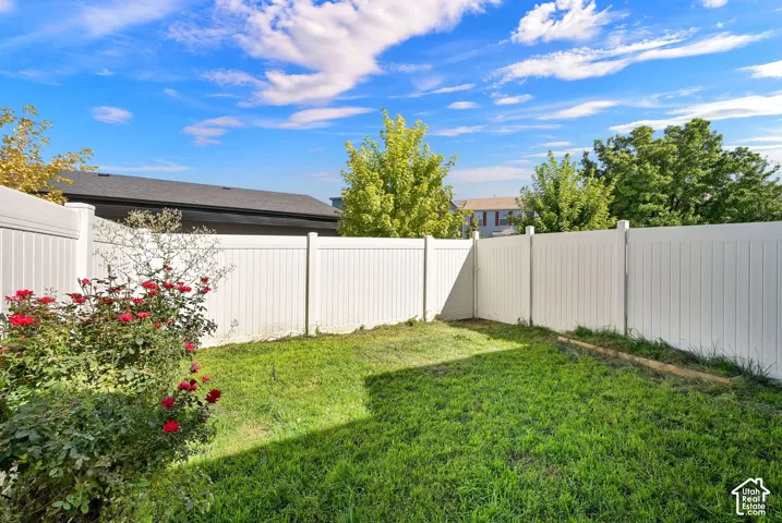 Private backyard space featuring a vinyl fence, green lawn, and established rose bushes