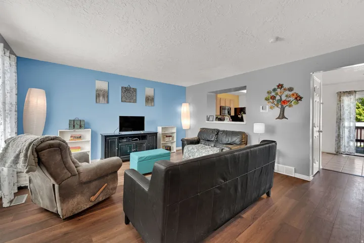 Wood-finish flooring throughout, light blue and gray wall tones, and a pass-through window to an adjacent room