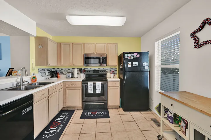 Kitchen featuring wood-finish cabinetry, tile flooring, and a window with blinds