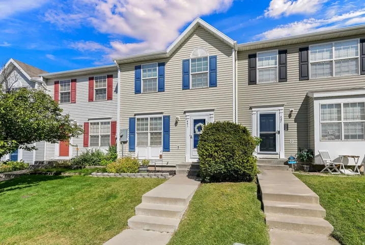 Townhome exterior featuring vinyl siding, contrasting shutters, concrete walkways, and a manicured lawn