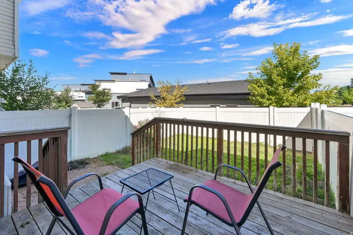 Expansive wood deck with railing and stairs overlooking a fenced yard with manicured lawn