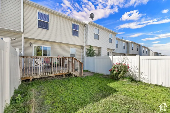 Private backyard with a wood deck, sliding glass door, and vinyl fencing