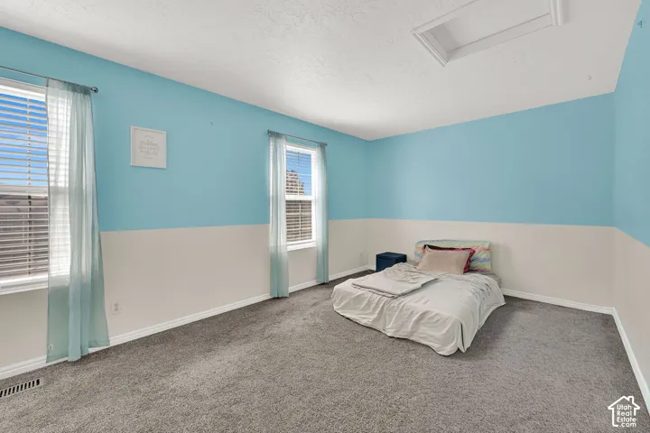 Carpeted room with two windows, two-tone wall paint, and a ceiling access panel