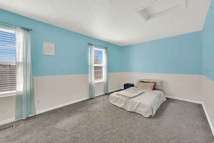 Carpeted room with two windows, two-tone wall paint, and a ceiling access panel