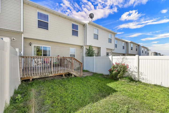 Private backyard with a wood deck, sliding glass door, and vinyl fencing