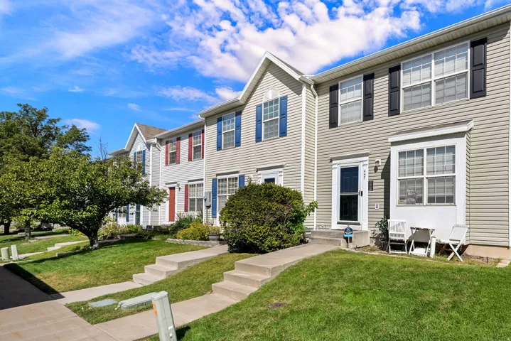 Vinyl siding exterior featuring contrasting window shutters, a prominent bay window, and a concrete walkway