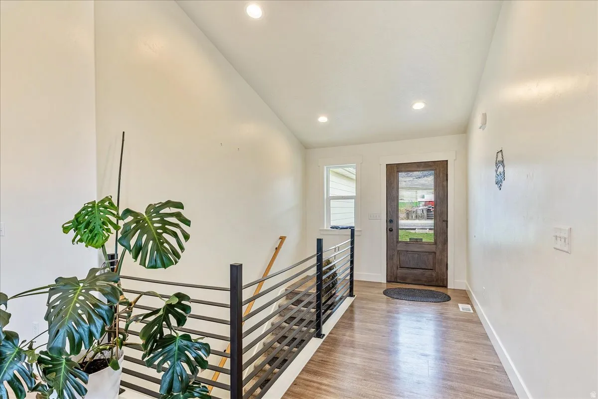 Wood-finish flooring, recessed lighting, and a dark wood entry door with a clear glass insert