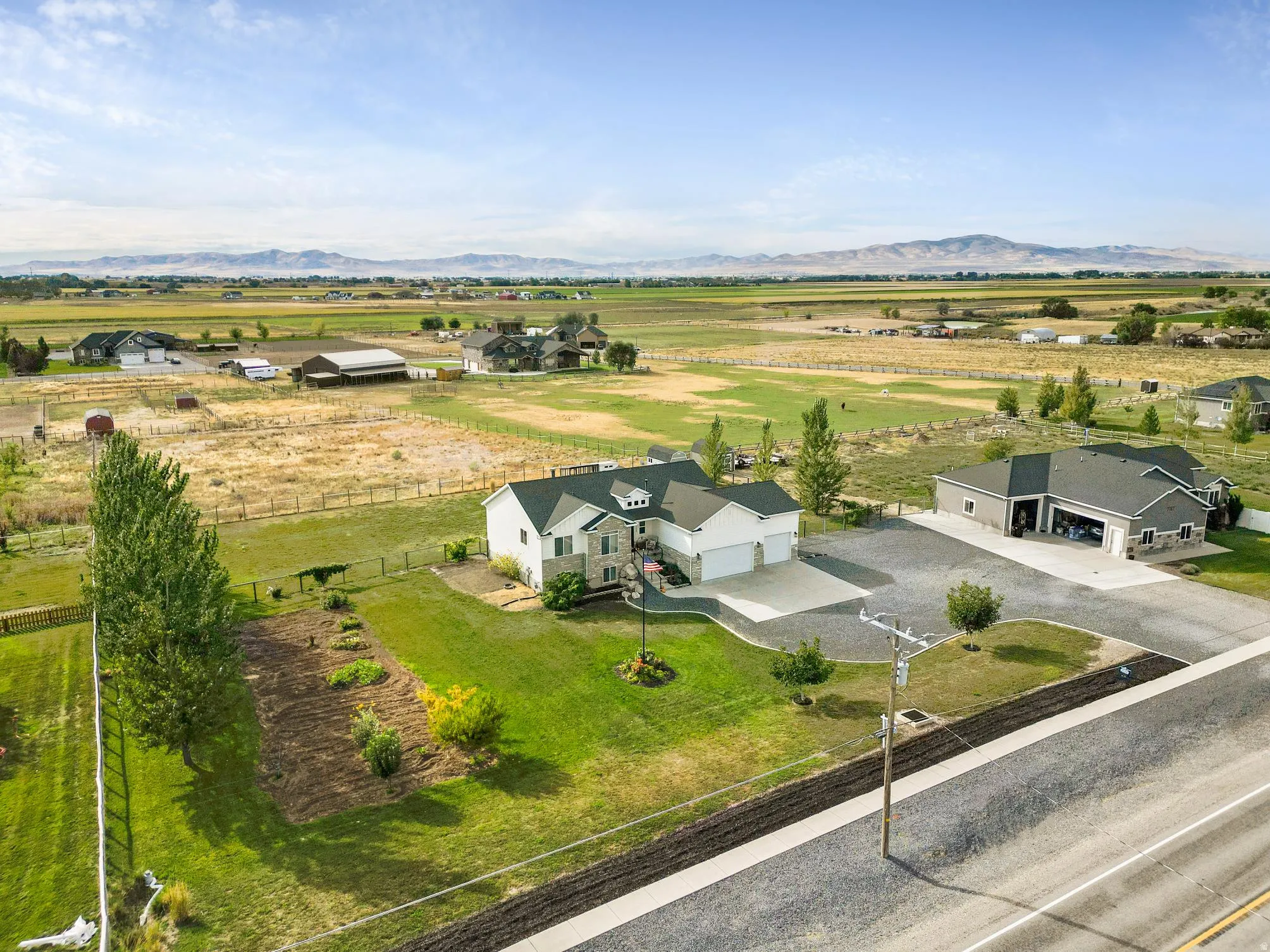 Two-story property featuring a stone and siding exterior, multi-car garage, and a large additional detached garage